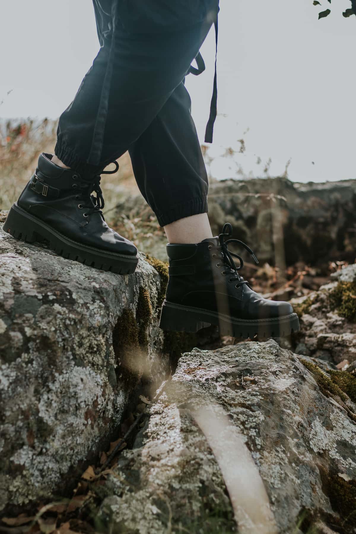 Black hiking boots planted on a rock, close up