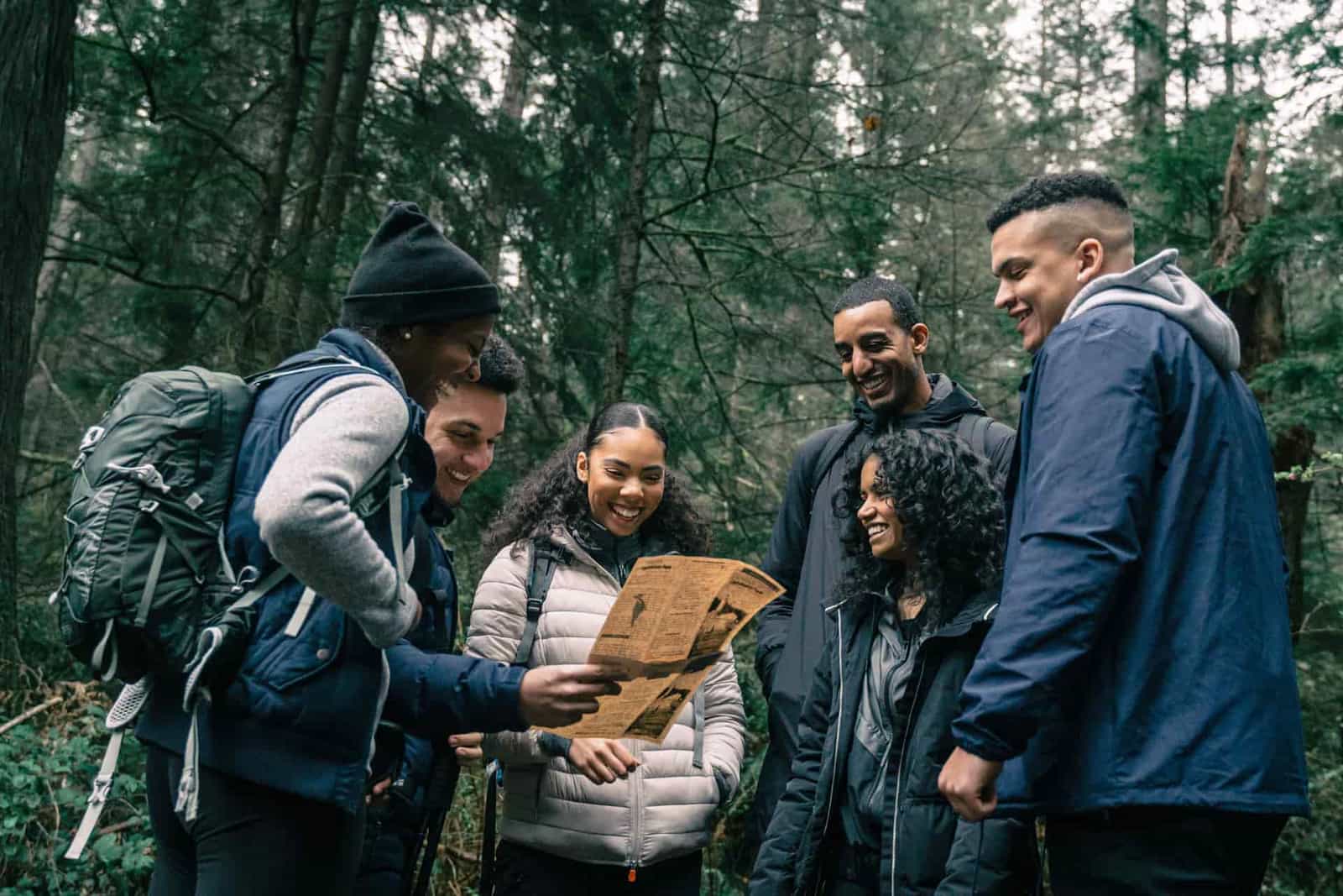 A group of hikers reading a map on a forest trail