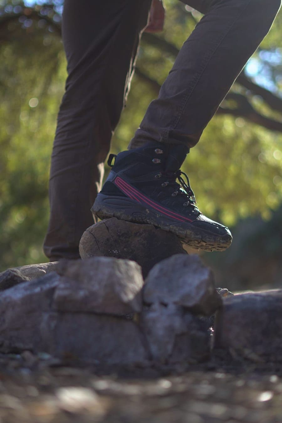 A hiking boot resting on rocks in a sunlit forest